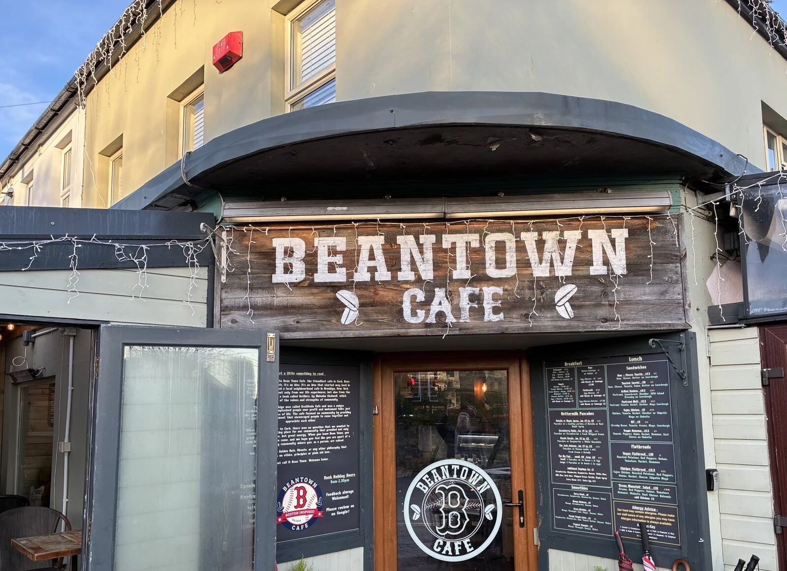 The Beantown Cafe timber sign over the door on Model Farm Road, with chalkboard menus either side