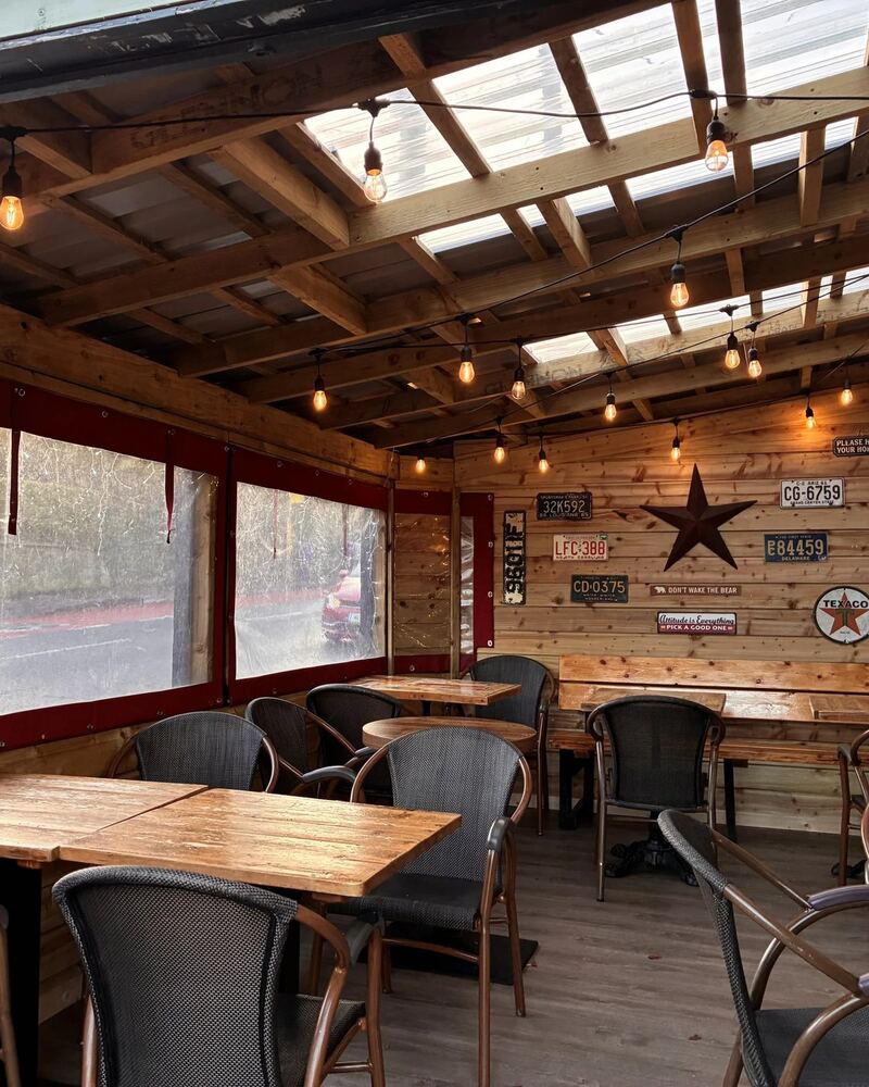 The covered timber seating area with string lights and licence plates on the wall